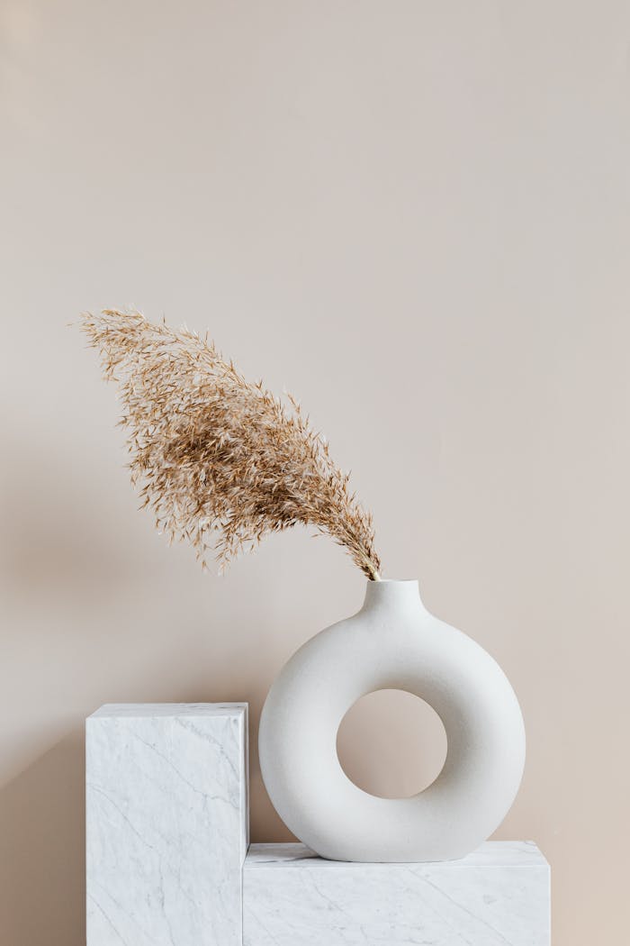 portfolio-02 Elegant ceramic vase with dried grass on a marble pedestal, showcasing simplicity and minimalism.